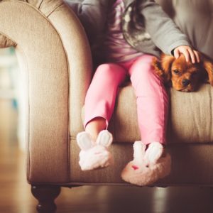 child sitting on sofa with dog