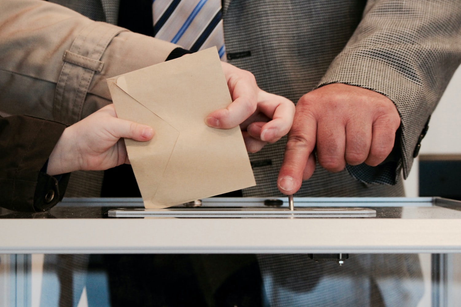 Hands putting a ballot into a voting box
